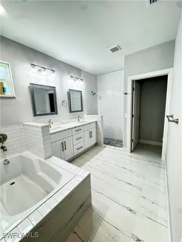 a spacious bathroom with a tub sink and mirror