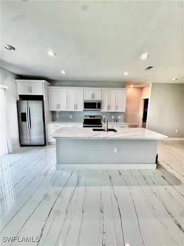 a large kitchen with stainless steel appliances granite countertop a large counter top a sink and a stove