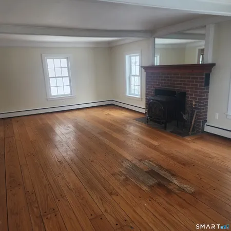 an empty room with wooden floor fireplace and windows