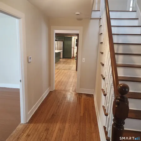 a view of a hallway with wooden floor and stairs