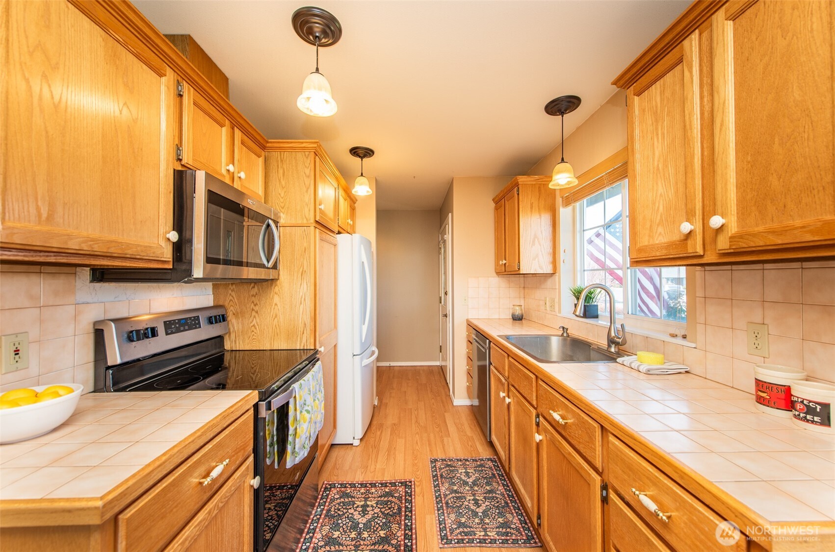 892 North Oxford Way Sequim, WA 98382 - Photo 11 of 38 a kitchen with stainless steel appliances a stove a sink dishwasher and cabinets with wooden floor