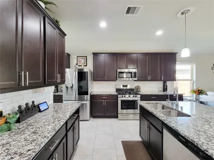 a large kitchen with granite countertop stainless steel appliances and wooden cabinets