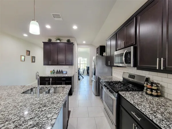 a kitchen with granite countertop kitchen island stainless steel appliances a stove sink and living room view