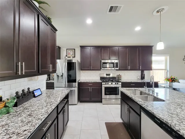 a large kitchen with granite countertop stainless steel appliances and wooden cabinets