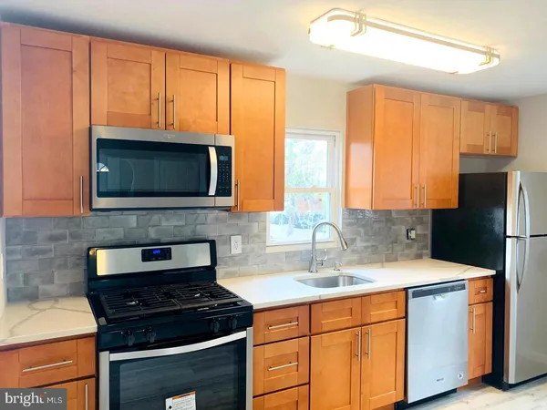 a kitchen with granite countertop a stove a sink and a microwave