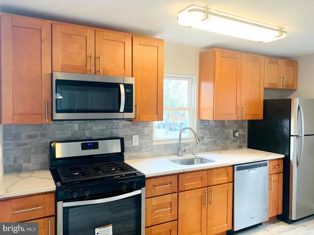 a kitchen with granite countertop a stove a sink and a microwave