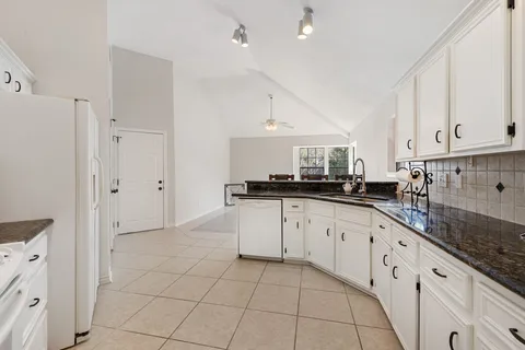 a kitchen with granite countertop white cabinets and white appliances
