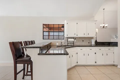 a kitchen with granite countertop white cabinets and white appliances