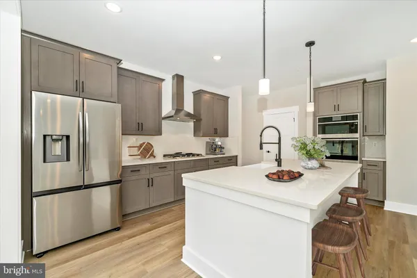 a kitchen with sink a refrigerator and a stove with wooden floor