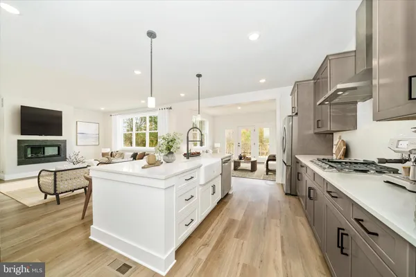 a kitchen with stainless steel appliances kitchen island granite countertop a stove a sink and a wooden floor