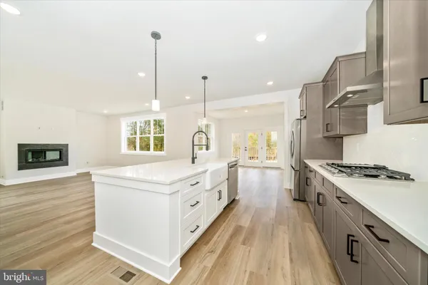 a kitchen with stainless steel appliances granite countertop a stove a sink dishwasher and a refrigerator with wooden floor