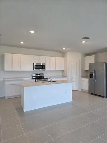 a large kitchen with stainless steel appliances granite countertop a stove a sink and a refrigerator