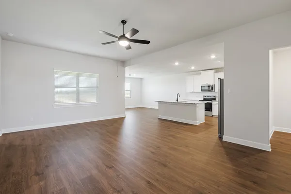a view of a livingroom with a ceiling fan window wooden floor and staircase