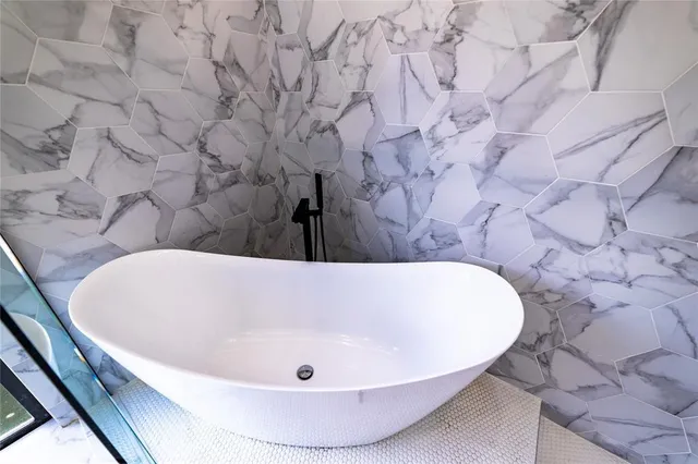a bathroom with a tub a sink and mirror