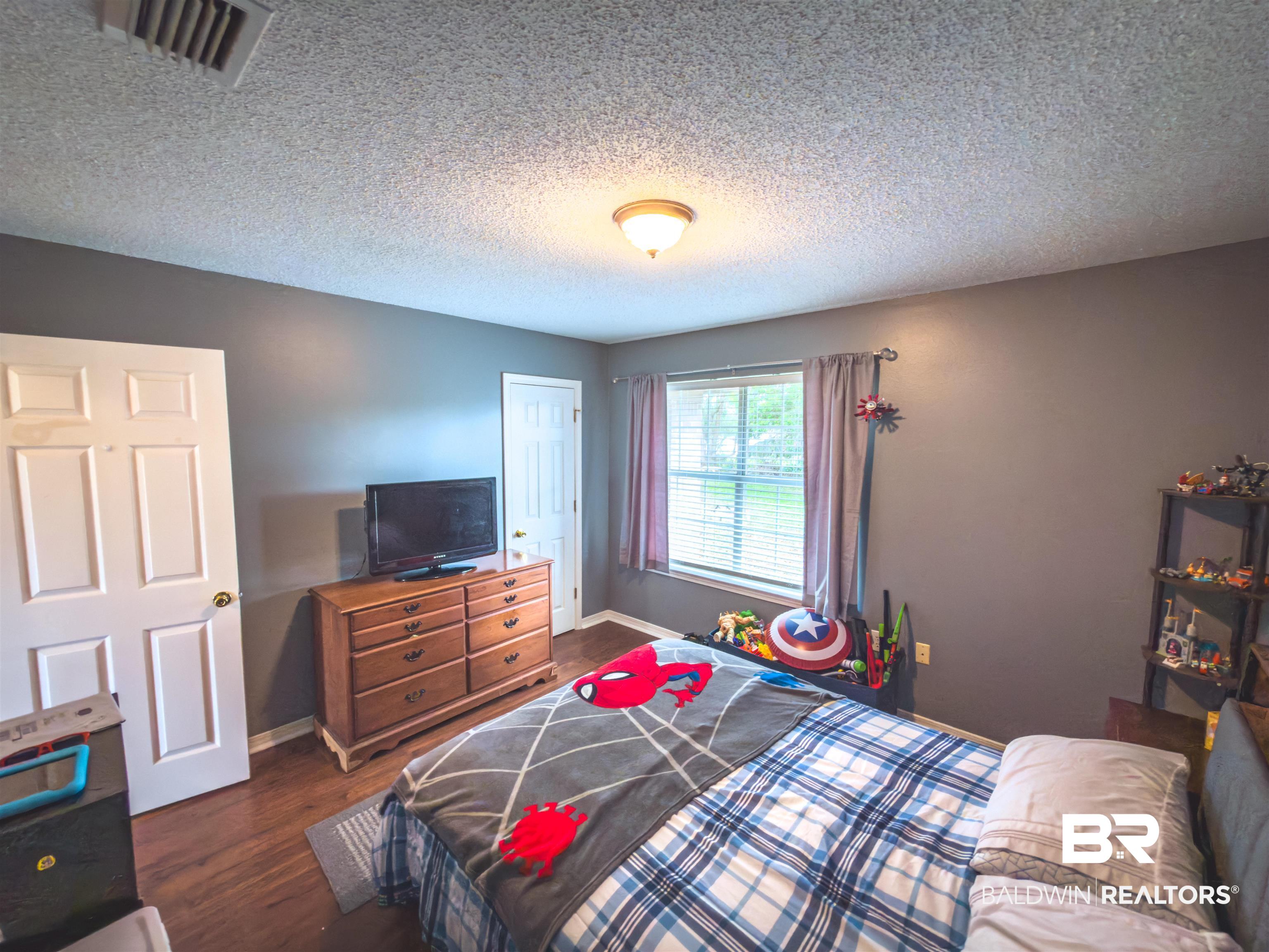 129 Pennbrooke Loop Foley, AL 36535 - Photo 16 of 44 Bedroom with dark wood finished floors, a textured ceiling, and a closet