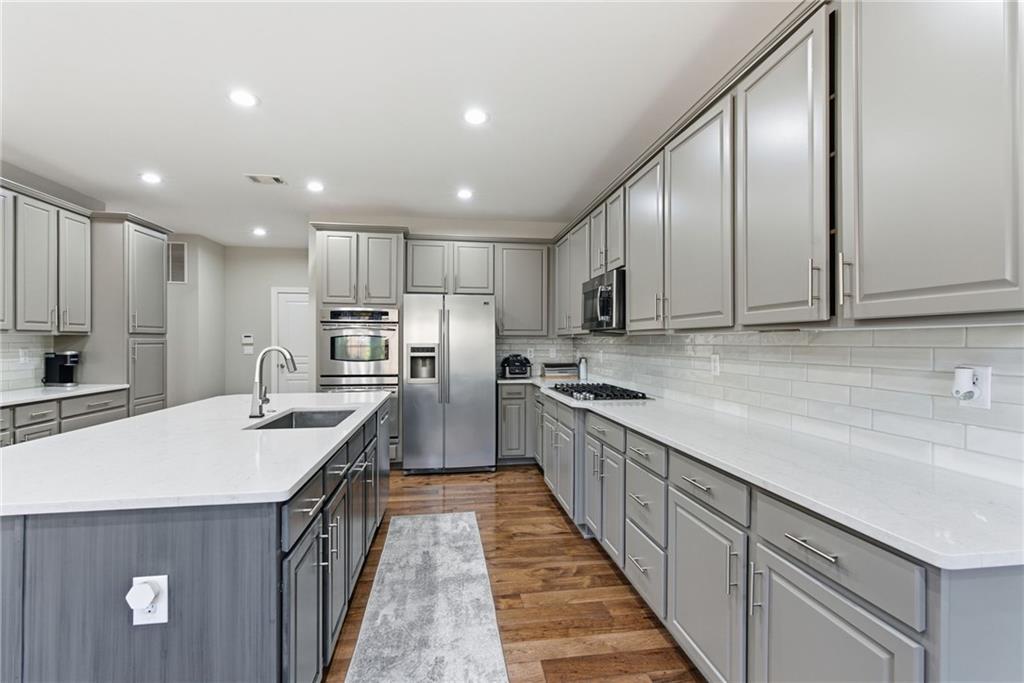 4415 Brampton Way Cumming, GA 30041 - Photo 20 of 59 a kitchen with kitchen island granite countertop wooden cabinets a sink a stove a oven and a refrigerator