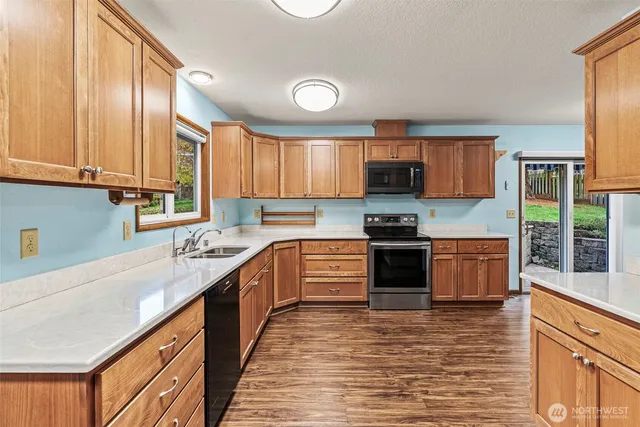 a kitchen with stainless steel appliances granite countertop a sink a stove cabinets counter space and a window
