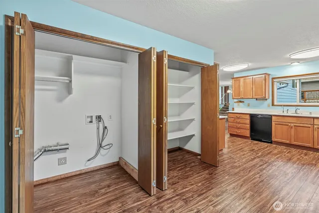 an empty room with wooden floor closet and windows