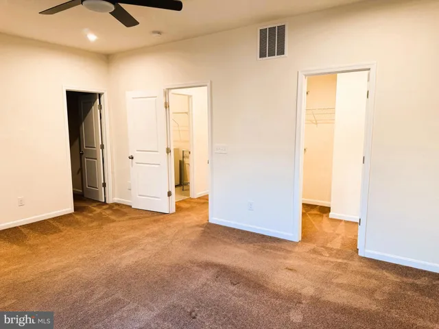 an empty room with closet and a chandelier fan