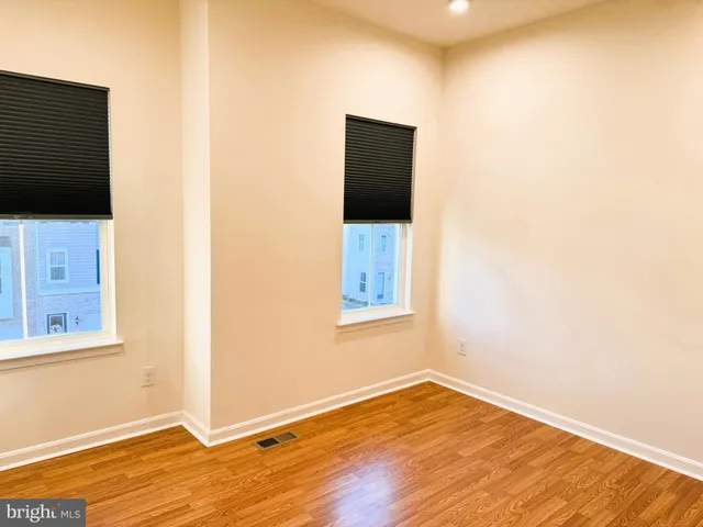 a view of an empty room with wooden floor and a flat screen tv