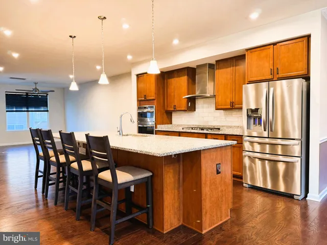 a kitchen with stainless steel appliances granite countertop a table chairs sink and cabinets