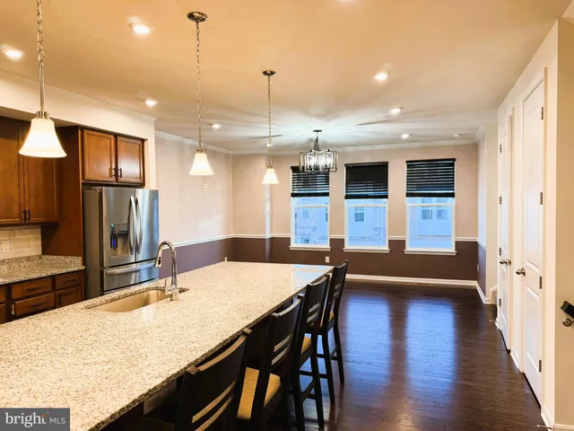 a dining hall with stainless steel appliances granite countertop wooden floor a dining table and chairs