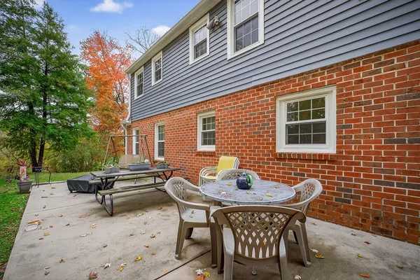 a backyard of a house with wooden table and chairs