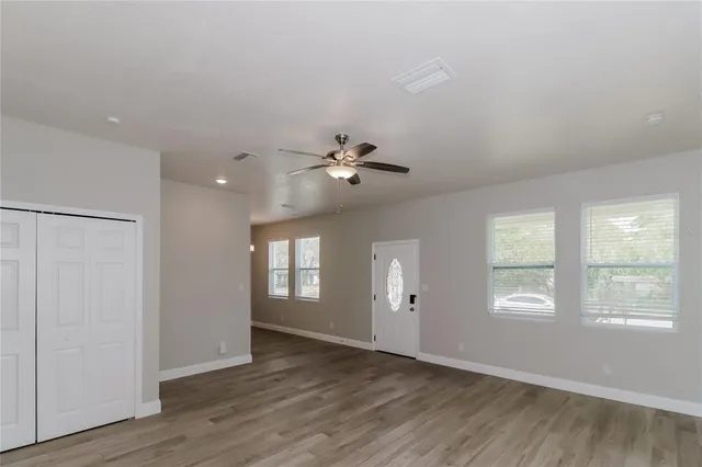 a view of an empty room with a window and wooden floor