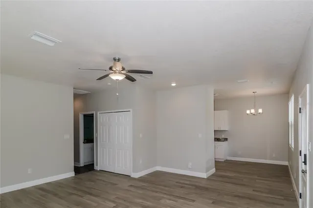 a view of an empty room with wooden floor and a ceiling fan