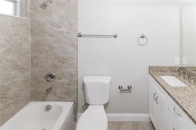 a bathroom with a granite countertop toilet a sink and bathtub