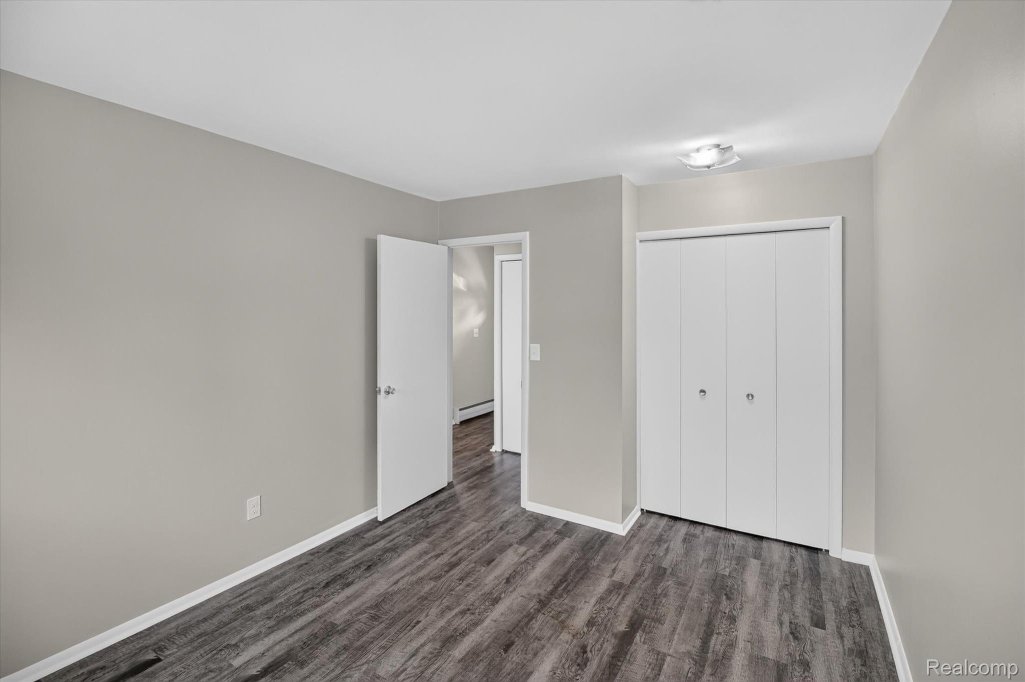 22000 Beck Road, Unit 101 Northville, MI 48167 - Photo 13 of 20 Wood-finish flooring, neutral wall tones, bi-fold closet doors, and overhead lighting