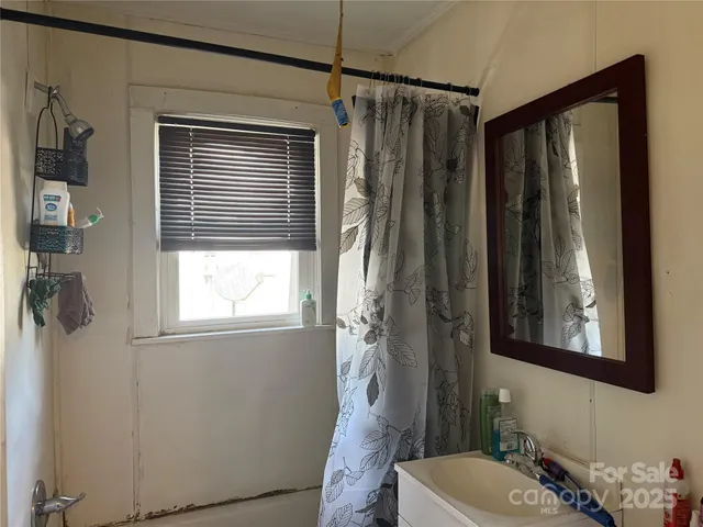 a bathroom with a granite countertop sink a mirror a window and a shower