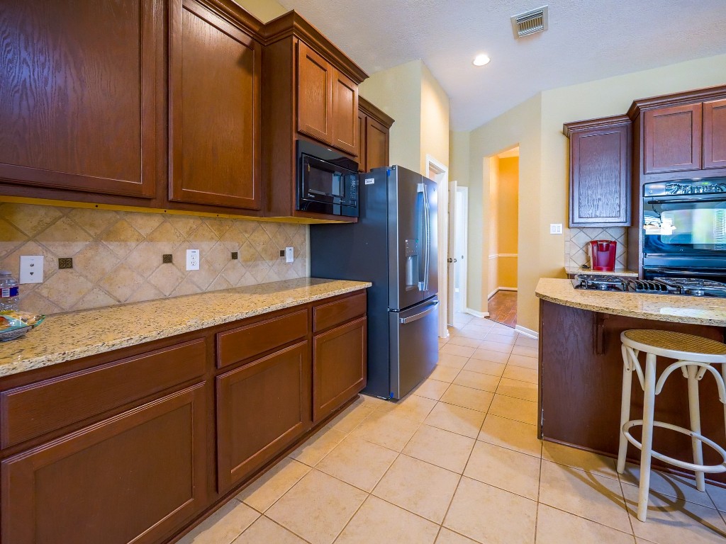 26173 Crown Ranch Boulevard Montgomery, TX 77316 - Photo 28 of 37 a kitchen with stainless steel appliances granite countertop a stove a sink and a microwave