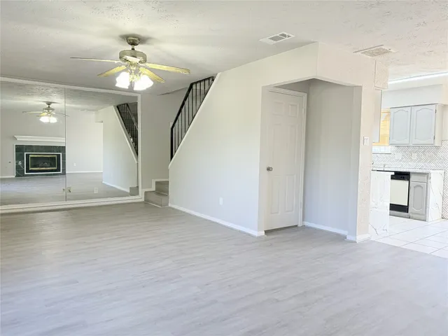 an empty room with wooden floor chandelier and windows