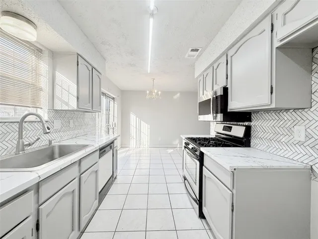 a kitchen with granite countertop a sink a stove and cabinets