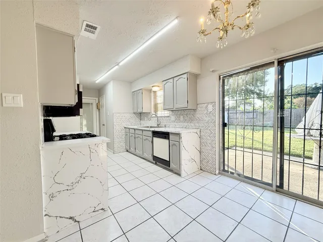 a kitchen with stainless steel appliances granite countertop a stove a sink dishwasher and white cabinets with wooden floor