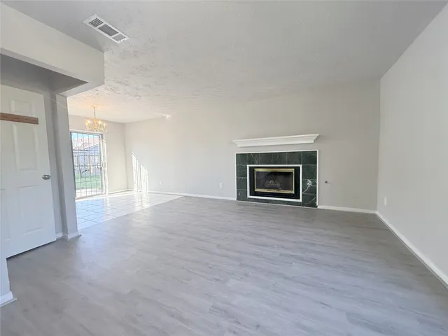 a view of an empty room with wooden floor fireplace and a window