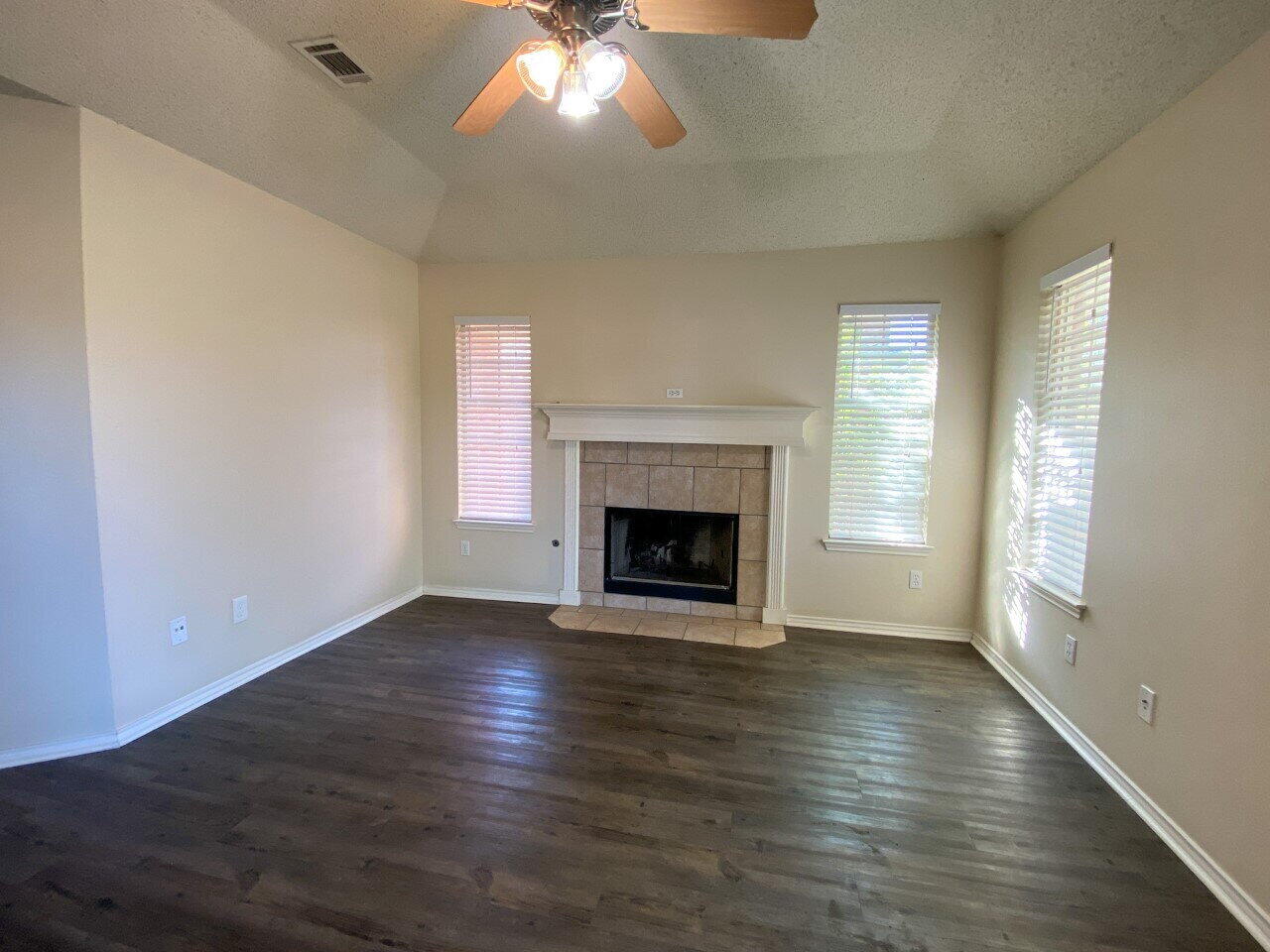 3209 110th Street, Unit B Lubbock, TX 79423 - Photo 3 of 7 a view of an empty room with wooden floor fireplace and a window