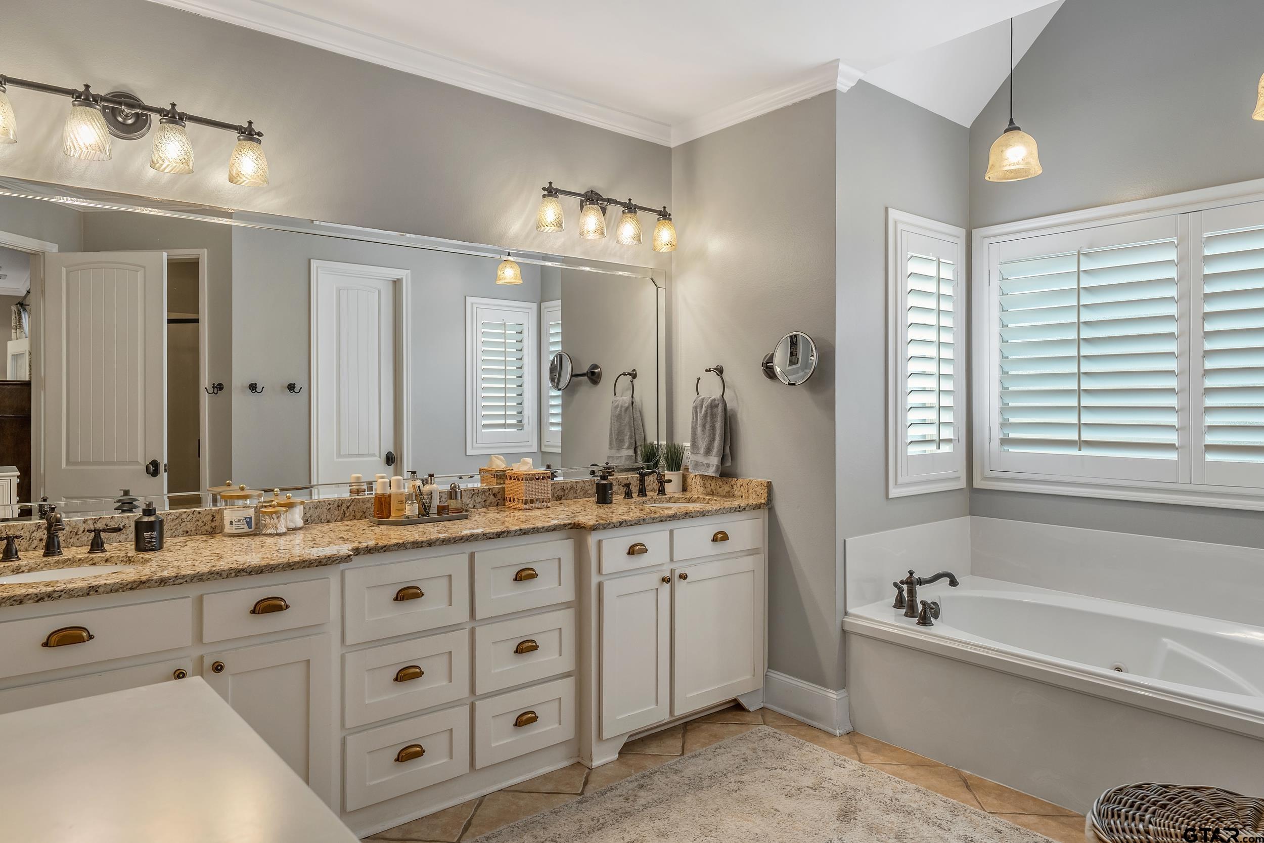 7752 Lamp Post Cove Tyler, TX 75703 - Photo 18 of 41 a bathroom with double vanity sinks a large mirror and a bathtub