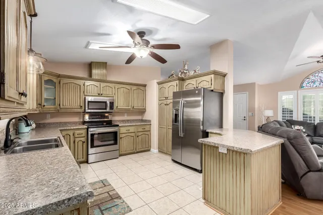 a kitchen with stainless steel appliances granite countertop a sink a stove a refrigerator a washer dryer and a dining table