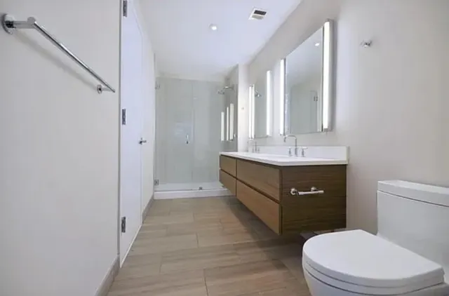a spacious bathroom with a double vanity sink toilet and a mirror