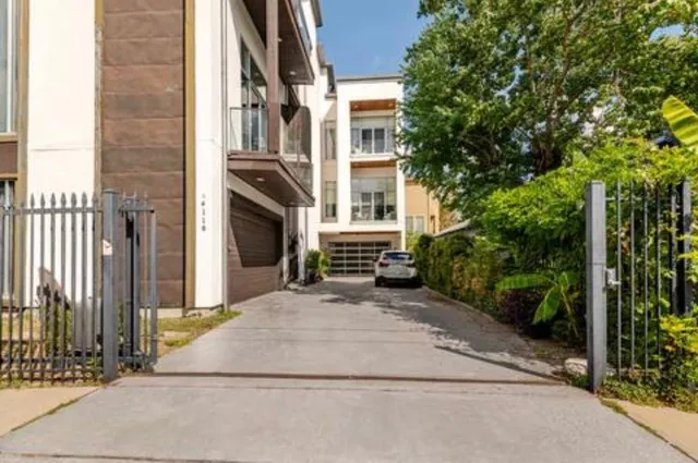 a view of a brick house with plants and large tree