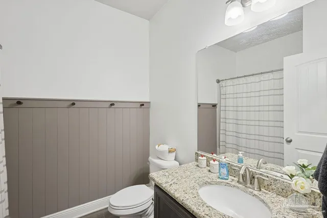 a bathroom with a granite countertop sink toilet a mirror and shower