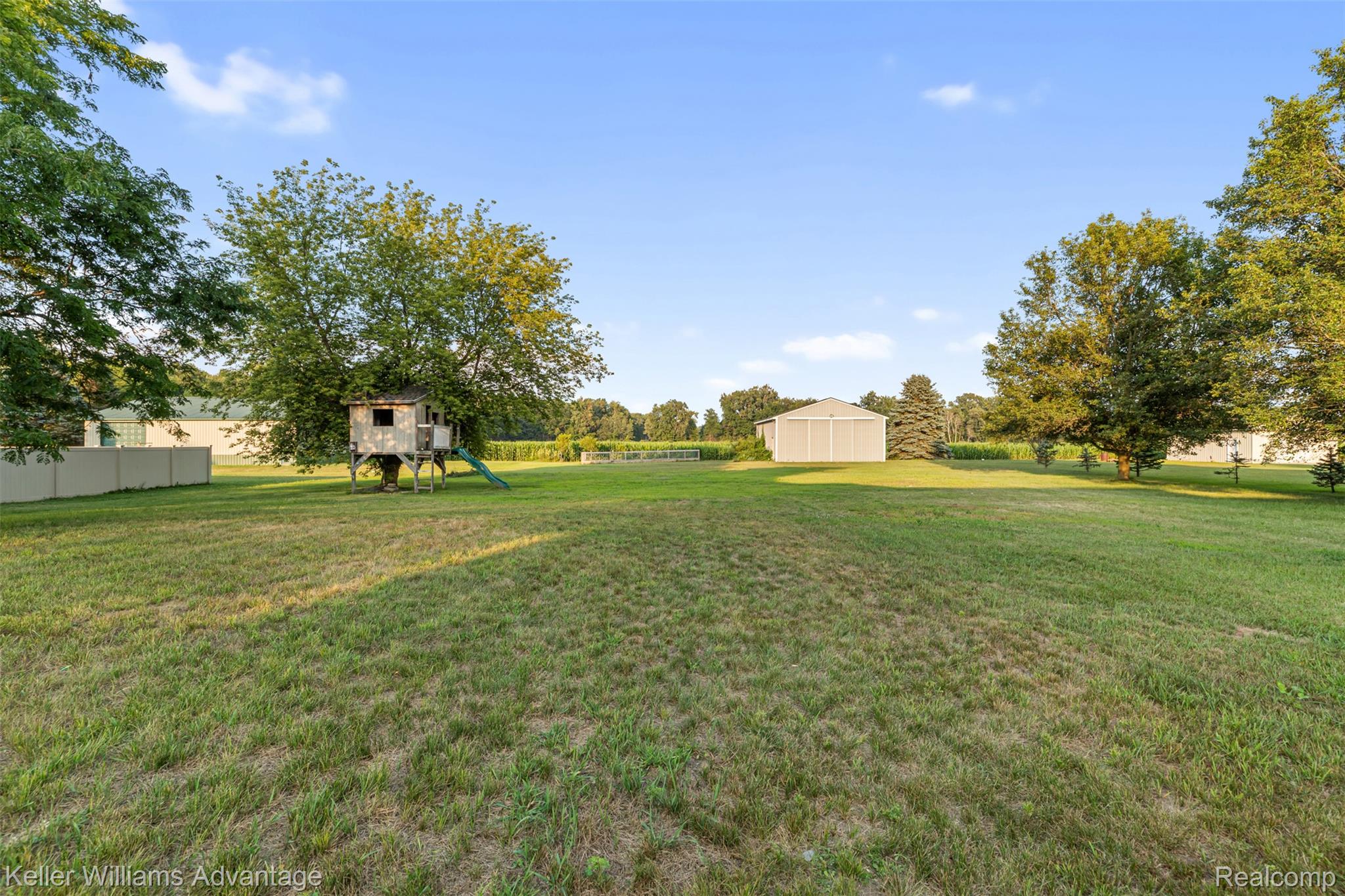 22627 Otter Road New Boston, MI 48164 - Photo 37 of 52 Expansive backyard featuring a manicured lawn, mature trees, and a treehouse structure with a slide