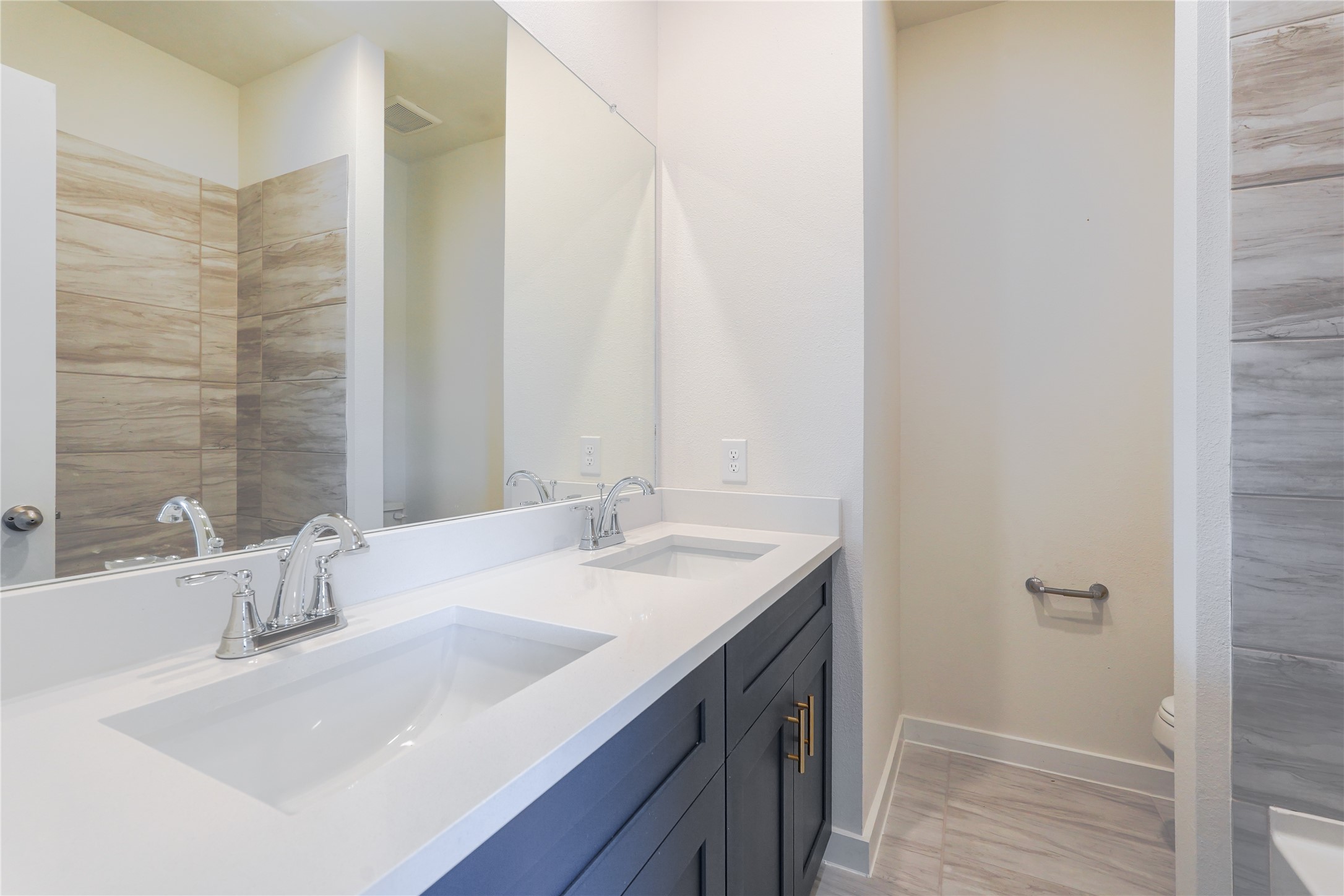 6618 Escondido Drive Rosharon, TX 77583 - Photo 22 of 31 This spacious bedroom features plush carpeting, neutral walls, and ample natural light from two large windows. It includes a ceiling fan for comfort and a set of double doors leading to an en-suite bathroom with modern fixtures.