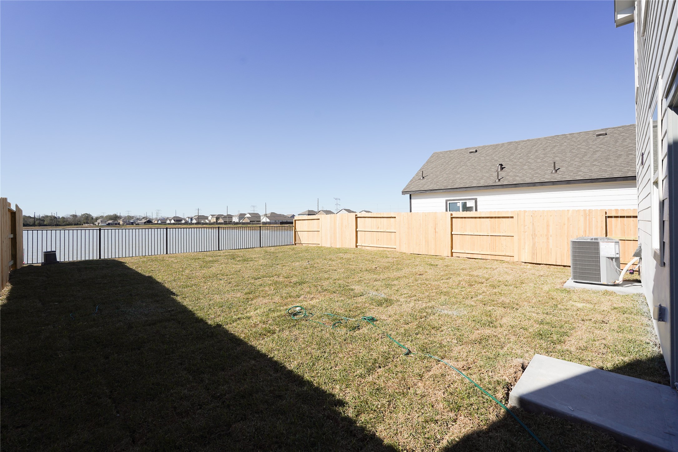 6618 Escondido Drive Rosharon, TX 77583 - Photo 27 of 31 Spacious backyard with a well-maintained lawn, wooden fencing for privacy, and a view of a nearby lake, perfect for outdoor activities and relaxation.