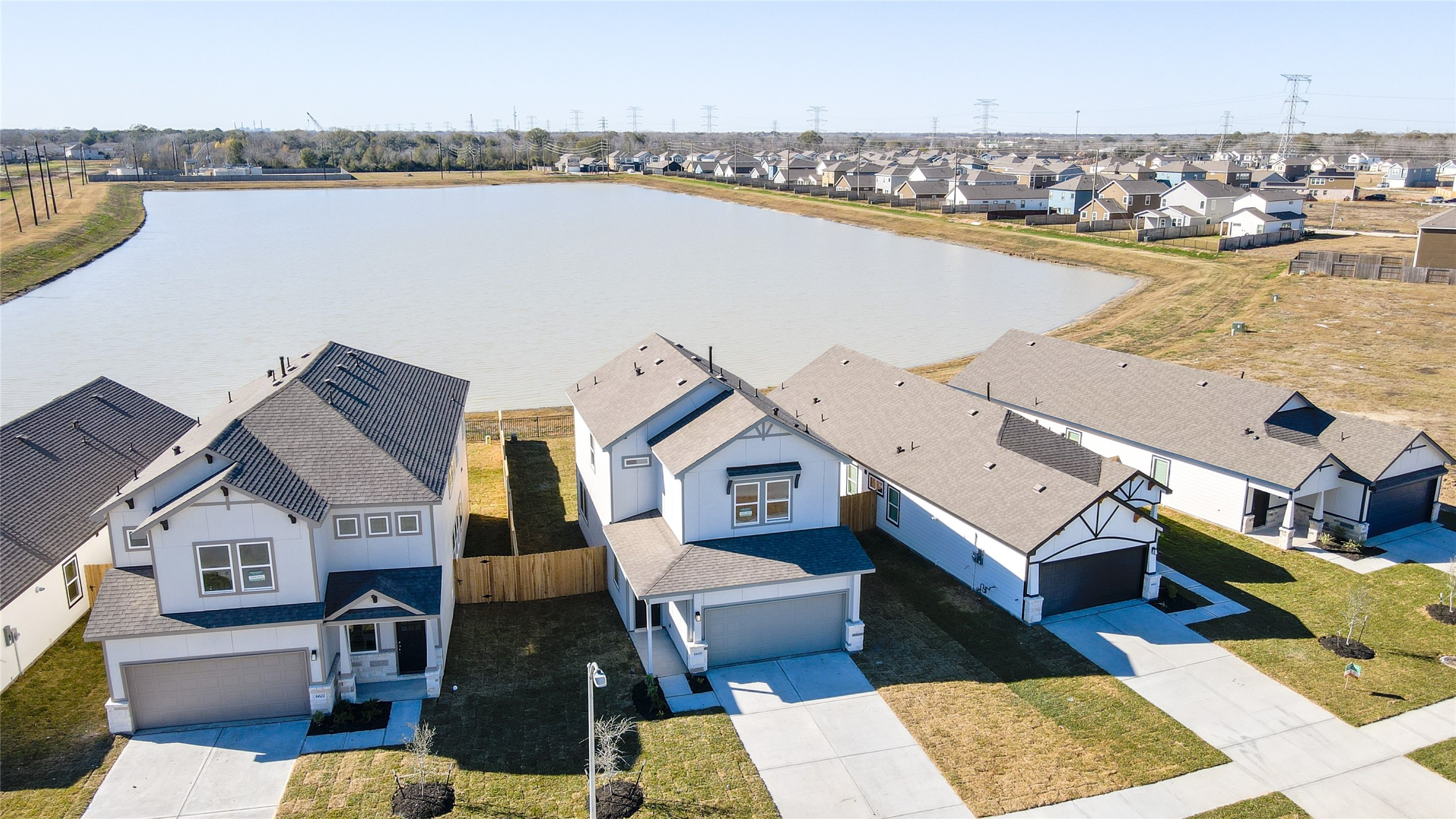 6618 Escondido Drive Rosharon, TX 77583 - Photo 29 of 31 This photo showcases modern homes in a serene neighborhood, situated along a large, peaceful lake. The properties feature well-maintained lawns and driveways, offering a picturesque and tranquil setting ideal for family living.