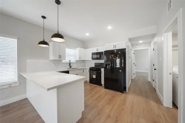 a large kitchen with a lot of counter space and wooden floor