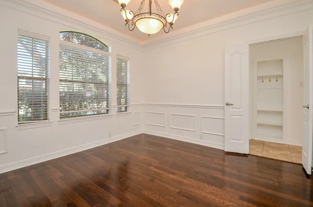 a view of an empty room with wooden floor fireplace and a window