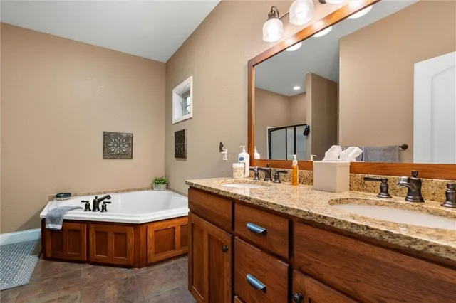 a spacious bathroom with a granite countertop sink a mirror and a bathtub